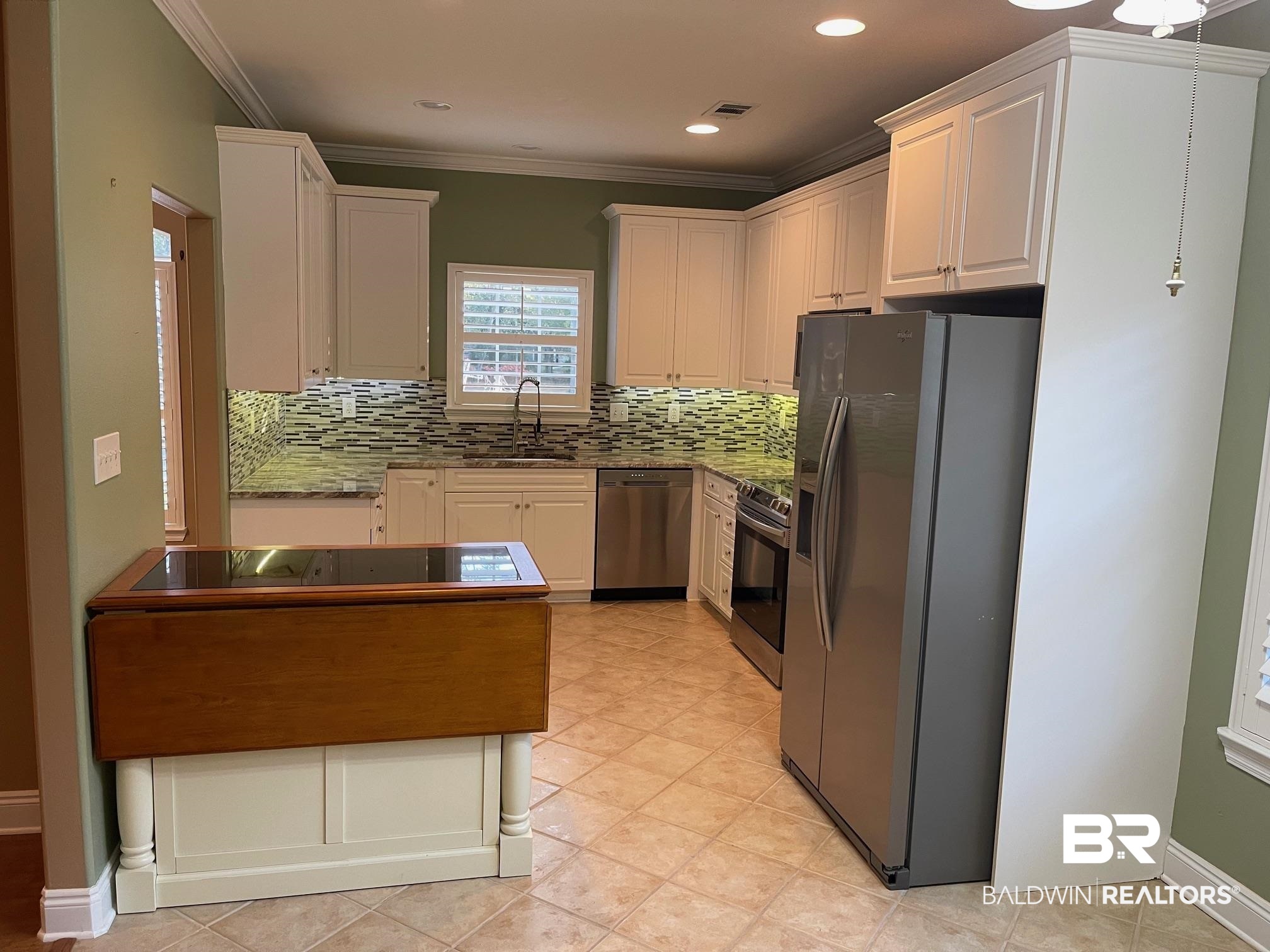 109 Savannah Circle Foley, AL 36535 - Photo 7 of 17 Kitchen with tasteful backsplash, ornamental molding, stainless steel appliances, sink, and white cabinetry