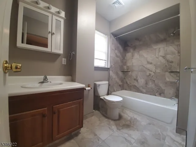 a bathroom with a granite countertop sink toilet and shower