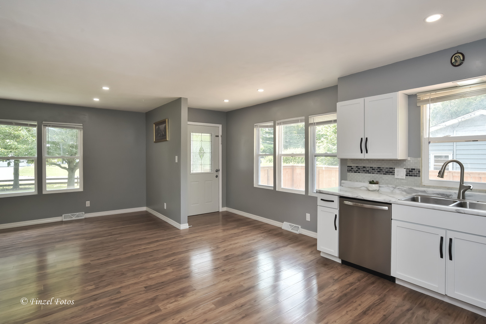 1009 Hickory Road Woodstock, IL 60098 - Photo 4 of 18 a kitchen with stainless steel appliances granite countertop white cabinets a sink a window and wooden floor