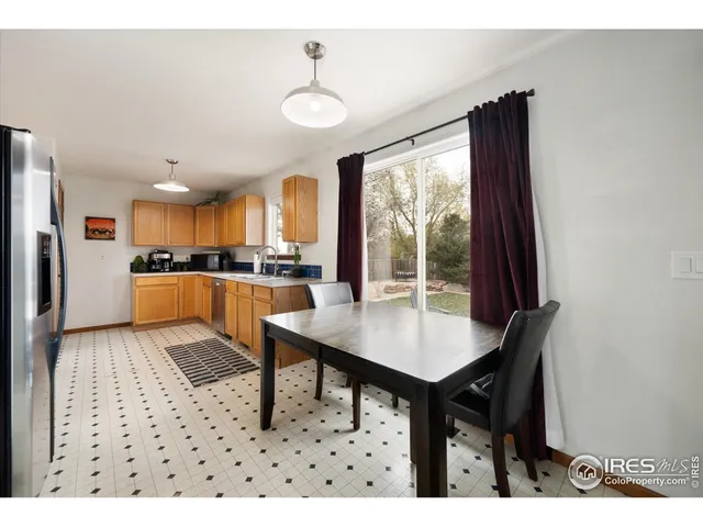a kitchen with stainless steel appliances kitchen island granite countertop a table chairs and a refrigerator