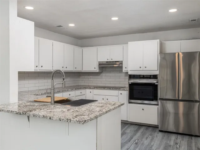 a kitchen with kitchen island granite countertop a sink cabinets and stainless steel appliances