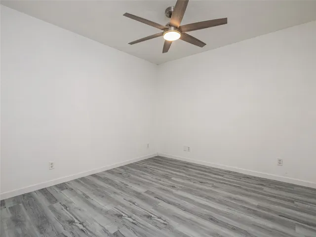 an empty room with wooden floor and a ceiling fan