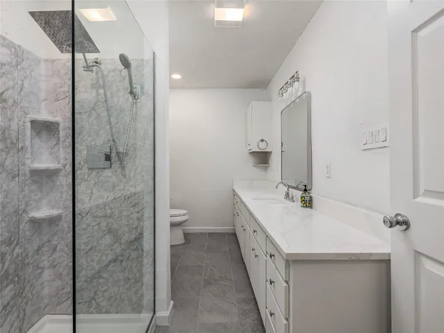 a bathroom with a double vanity sink toilet and shower