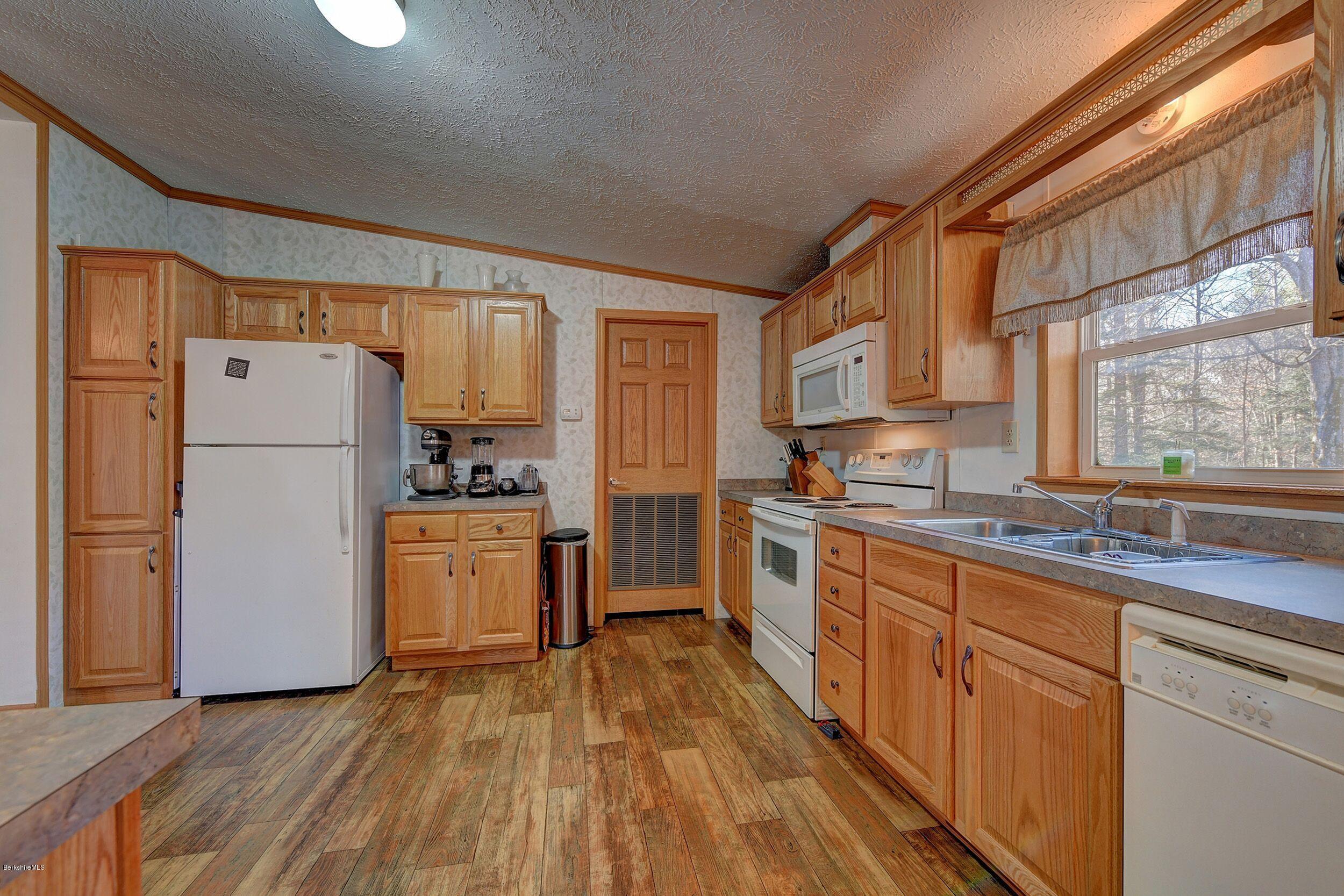 548 Loop Road Savoy, MA 01256 - Photo 4 of 12 a kitchen with a refrigerator a sink and dishwasher with wooden floor