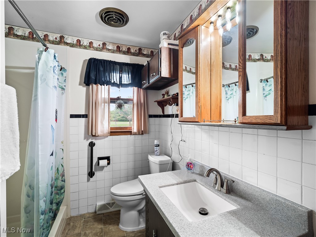 9049 Oberlin Road Elyria, OH 44035 - Photo 19 of 42 Full bath featuring vanity, tile walls, dark tile patterned floors, and shower / tub combo