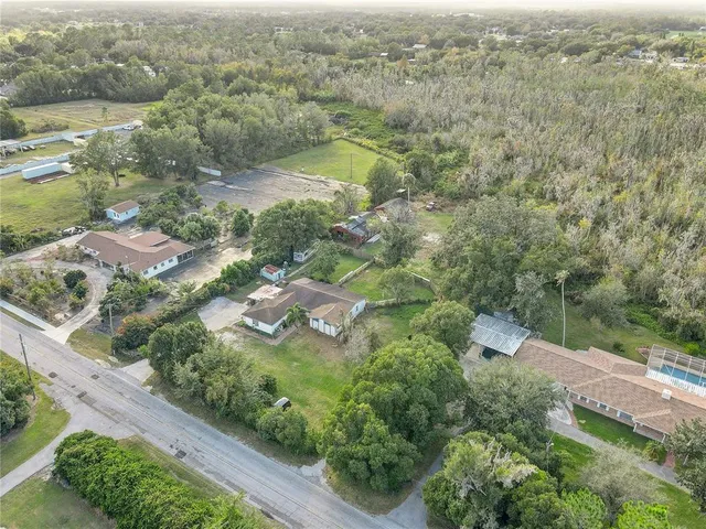 an aerial view of residential houses with outdoor space and trees