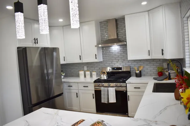 a kitchen with stainless steel appliances a refrigerator a sink a stove and white cabinets