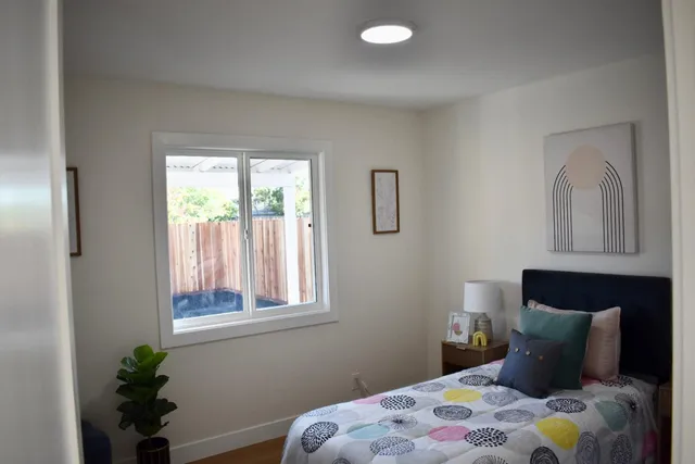 a bedroom with a bed lamp and a potted plant