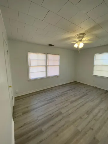 an empty room with wooden floor and windows