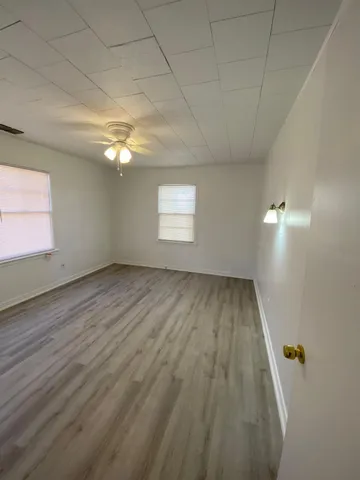 an empty room with wooden floor and windows