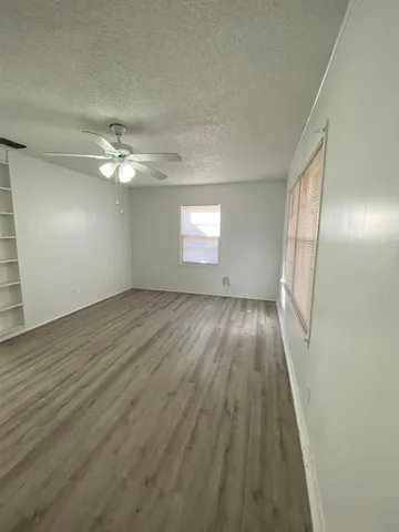 a view of an empty room with wooden floor and window