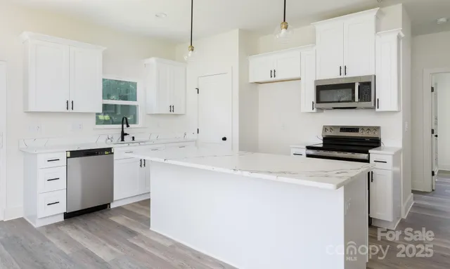 a kitchen with stainless steel appliances a stove a sink and white cabinets