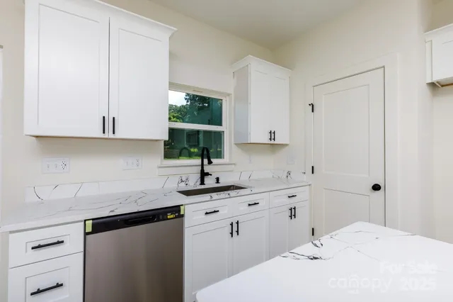 a kitchen with a sink dishwasher window and cabinets
