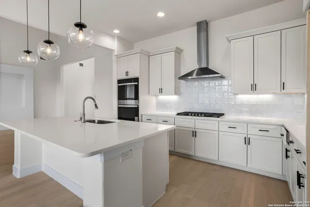 a kitchen that has a lot of white cabinets and stainless steel appliances