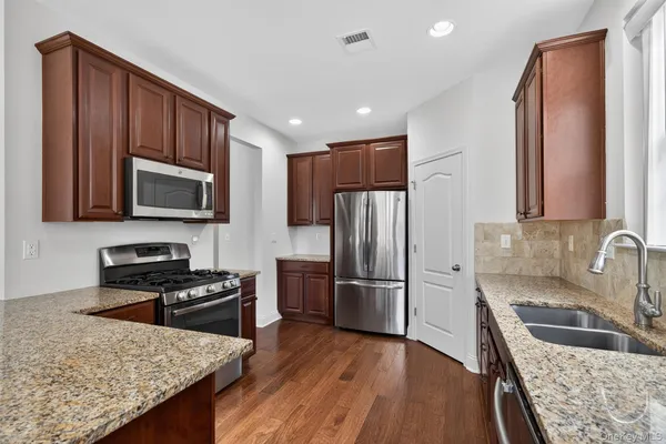 a kitchen with granite countertop wooden cabinets a refrigerator and a sink