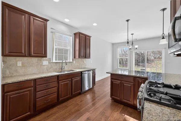 a kitchen with stainless steel appliances granite countertop wooden cabinets stove top oven and sink
