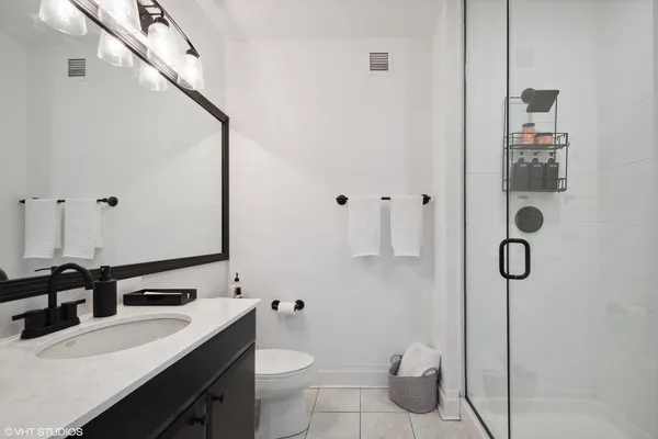a bathroom with a granite countertop sink mirror vanity and toilet