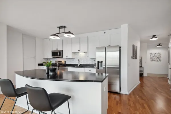 a kitchen with kitchen island a counter top space a sink stainless steel appliances and cabinets