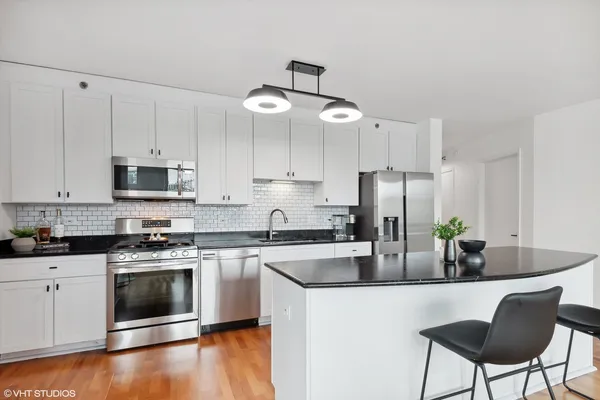 a kitchen with stainless steel appliances a stove a sink and white cabinets