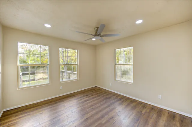 a view of an empty room with a window and wooden floor