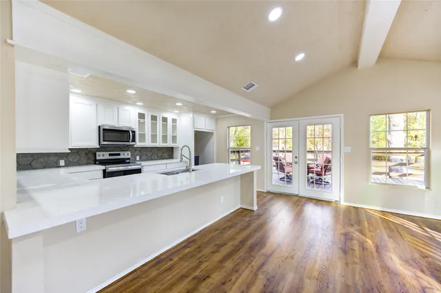 a large white kitchen with lots of counter top space a sink and appliances