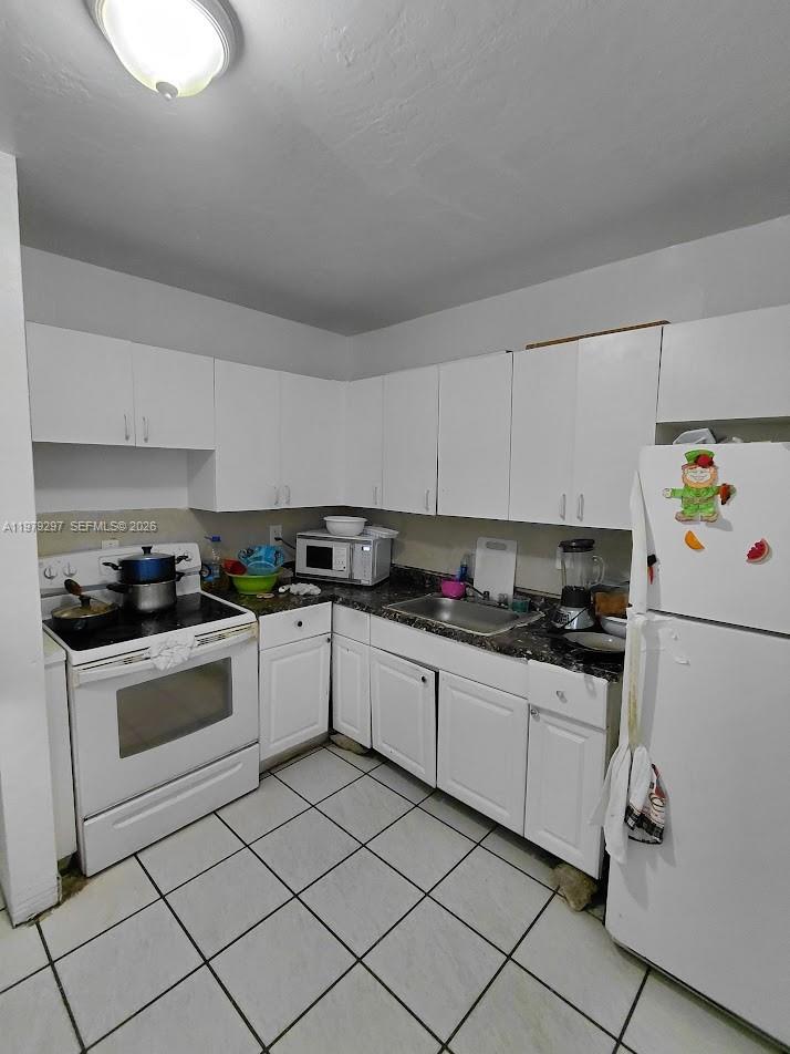1262 Northwest 46th Street Miami, FL 33142 - Photo 5 of 11 a kitchen with granite countertop cabinets and white appliances