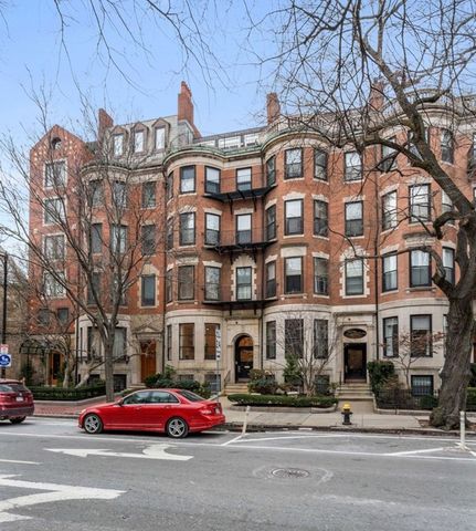 a front view of a building with lot of cars and trees