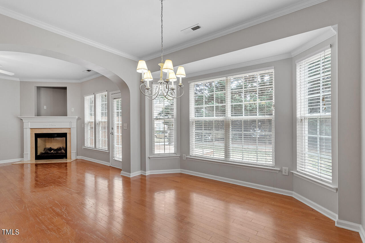 8403 Tie Stone Way Raleigh, NC 27613 - Photo 8 of 37 a view of an empty room with wooden floor fireplace and a window
