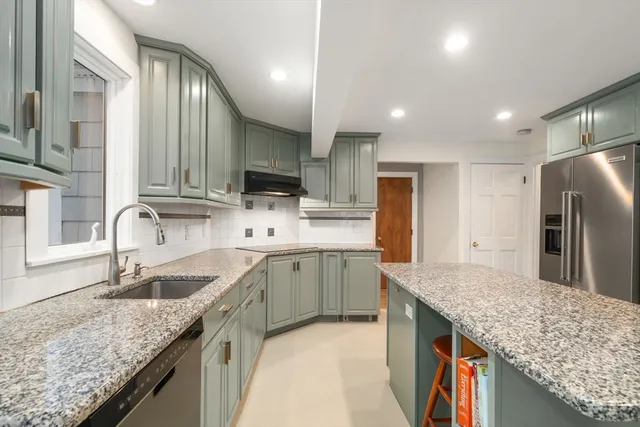 a kitchen with stainless steel appliances granite countertop a sink refrigerator and cabinets