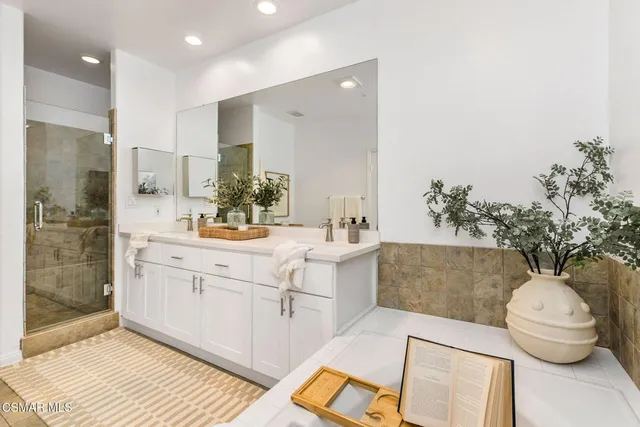 a spacious bathroom with a double vanity sink a large mirror and a shower