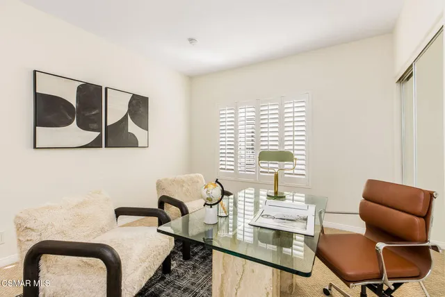 a view of a workspace with furniture and a window