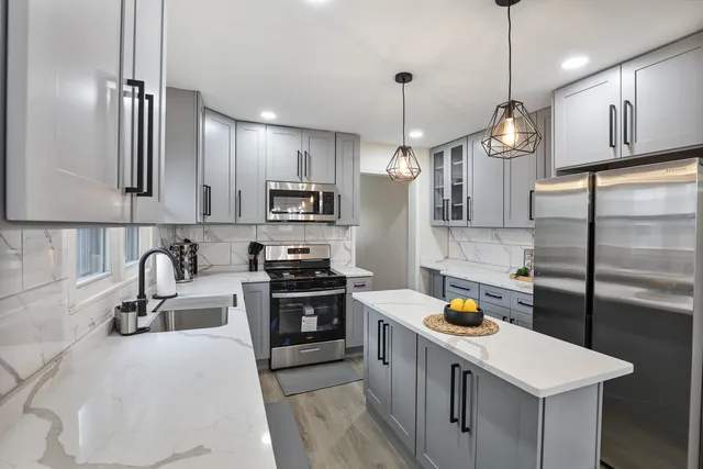 a kitchen with stainless steel appliances a sink a stove a refrigerator a center island and cabinets