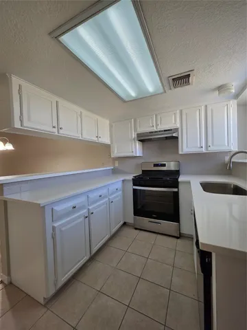 a kitchen with granite countertop a sink a stove and cabinets