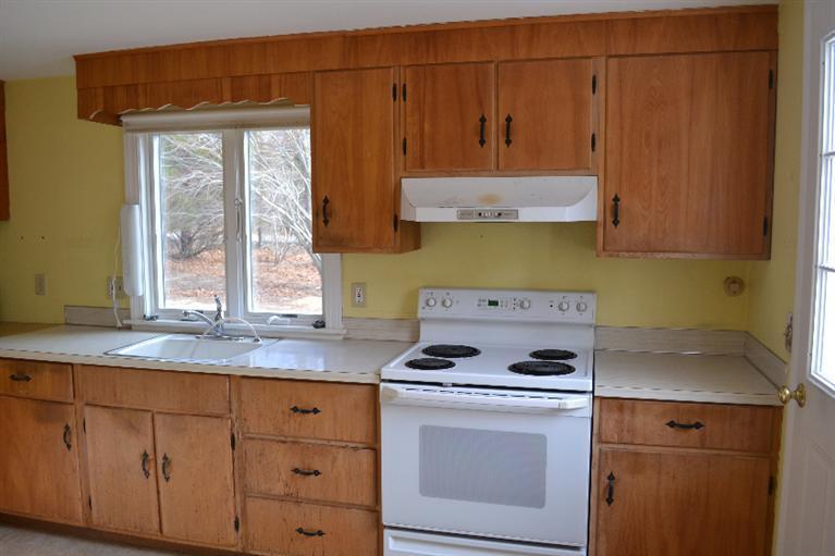 1755 Bridge Road Eastham, MA 02642 - Photo 5 of 10 a kitchen with granite countertop cabinets a stove a sink and a dishwasher with wooden cabinets