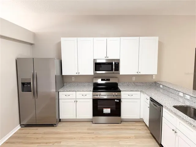 a kitchen with stainless steel appliances granite countertop a stove a refrigerator and a microwave