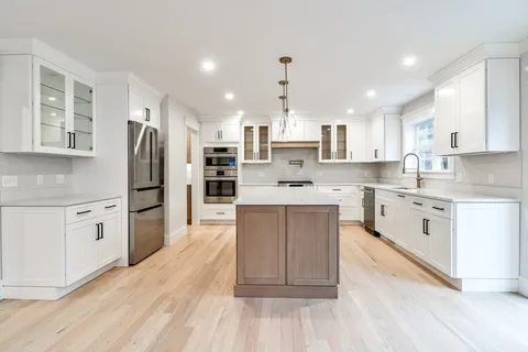 a kitchen with stainless steel appliances white cabinets a sink a stove a refrigerator and cabinets
