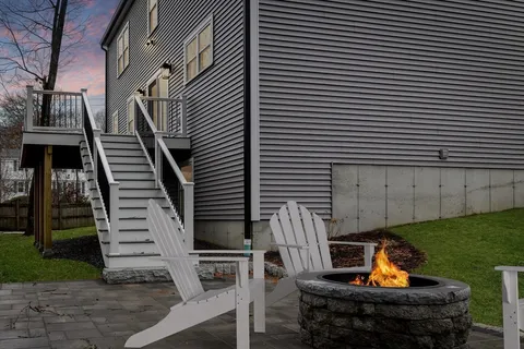 a backyard of a house with wooden chairs and a fire pit