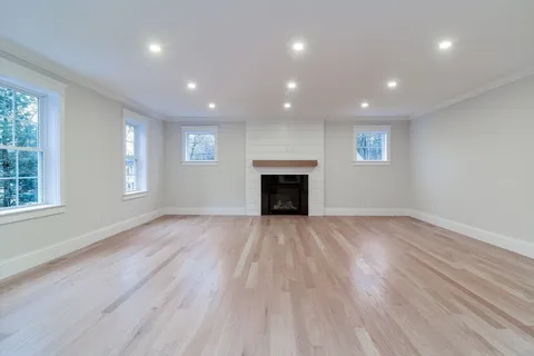 an empty room with wooden floor and a fireplace