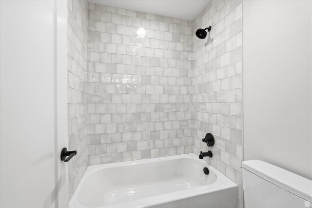 134 South Chamberlain Street Mapleton, UT 84664 - Photo 25 of 40 Clean, modern bathroom featuring subway tile surround with contrasting grout lines, a white soaking tub with matte black fixtures, and dual showerheads for versatile bathing options