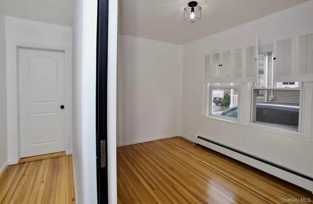 a view of an empty room with a window and wooden floor