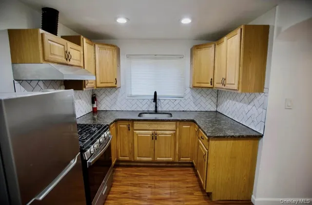 a kitchen with stainless steel appliances granite countertop a sink a stove and a refrigerator