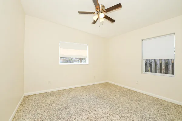 an empty room with a window and a ceiling fan