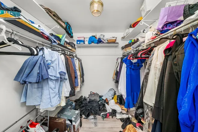 a view of walk in closet with clothes and shoes