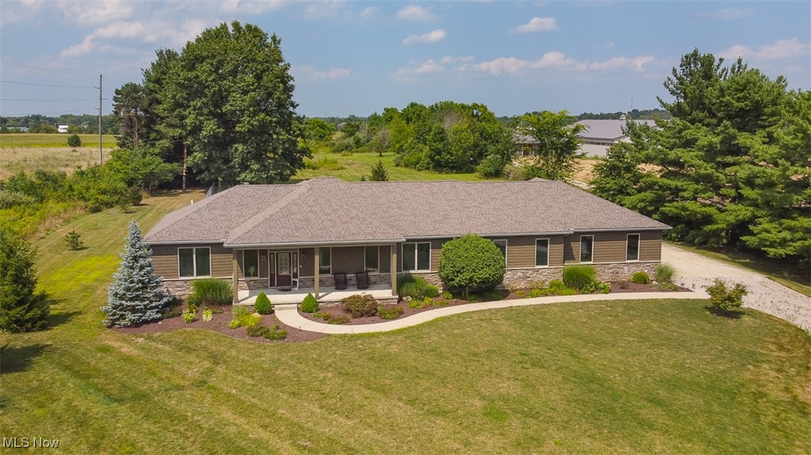 9155 Shank Road Litchfield, OH 44253 - Photo 1 of 47 Ranch-style house with stone siding, a front lawn, gravel driveway, and a shingled roof