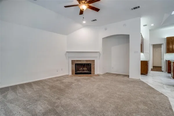 an empty room with fan and kitchen view