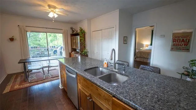 a kitchen with kitchen island granite countertop a sink dishwasher a dining table and chairs with wooden floor