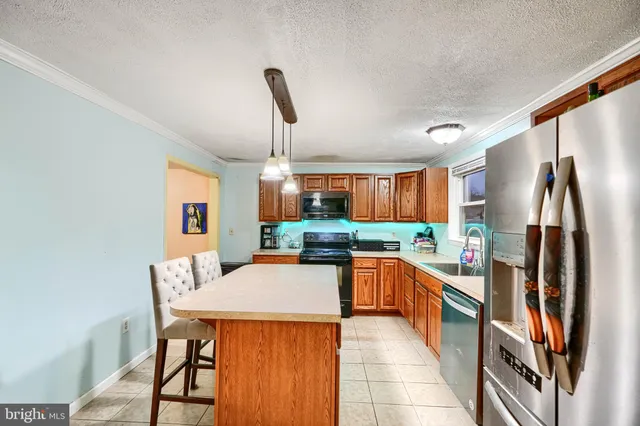 a kitchen with stainless steel appliances granite countertop a refrigerator a sink dishwasher a stove and a dining table with wooden floor