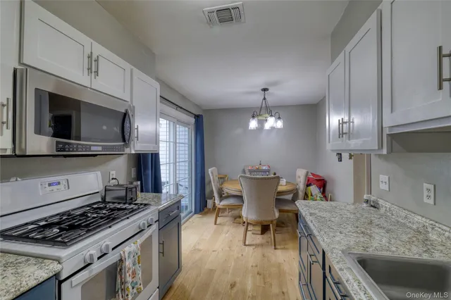 a kitchen with stainless steel appliances granite countertop a stove top oven a sink dishwasher a dining table and chairs with wooden floor