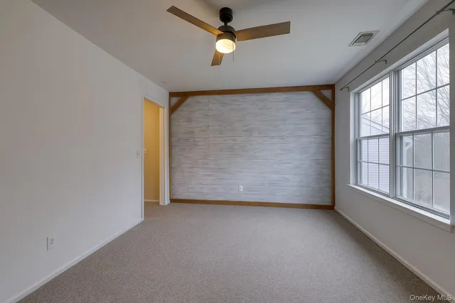 an empty room with ceiling fan and windows