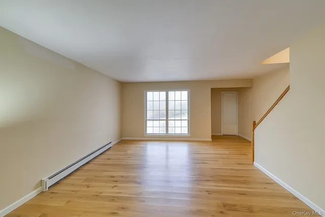 a view of an empty room with wooden floor and window